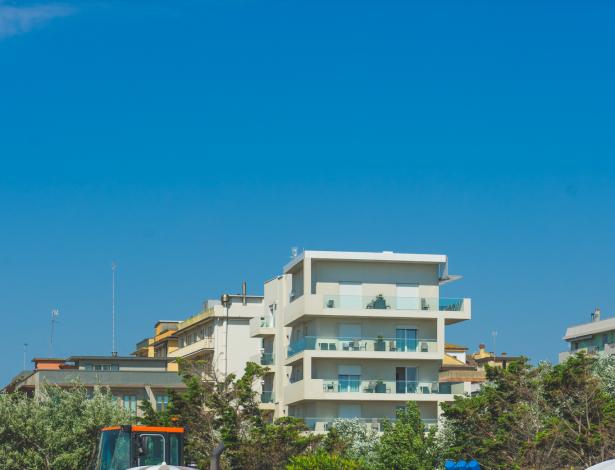 Piscina azzurra, sedie a sdraio e palazzi moderni sotto un cielo sereno.